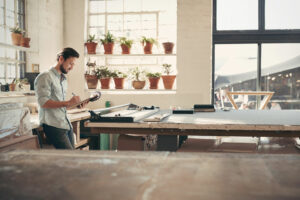 self-employed man reviewing inventory in studio workshop, cash flow management services, Alexander & Co.